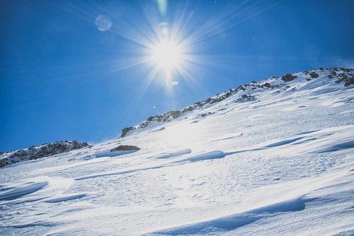 氷化した雪山の斜面と太陽の写真