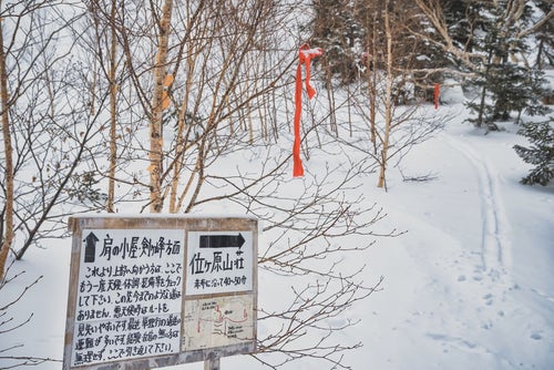 雪の中の位ヶ原山荘への看板と道しるべ（乗鞍岳）の写真