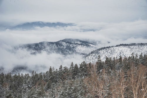 覆われた雲の中から顔を出す雪山の写真