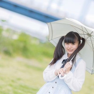 日傘をさして笑顔で微笑むツインテールの女の子の写真
