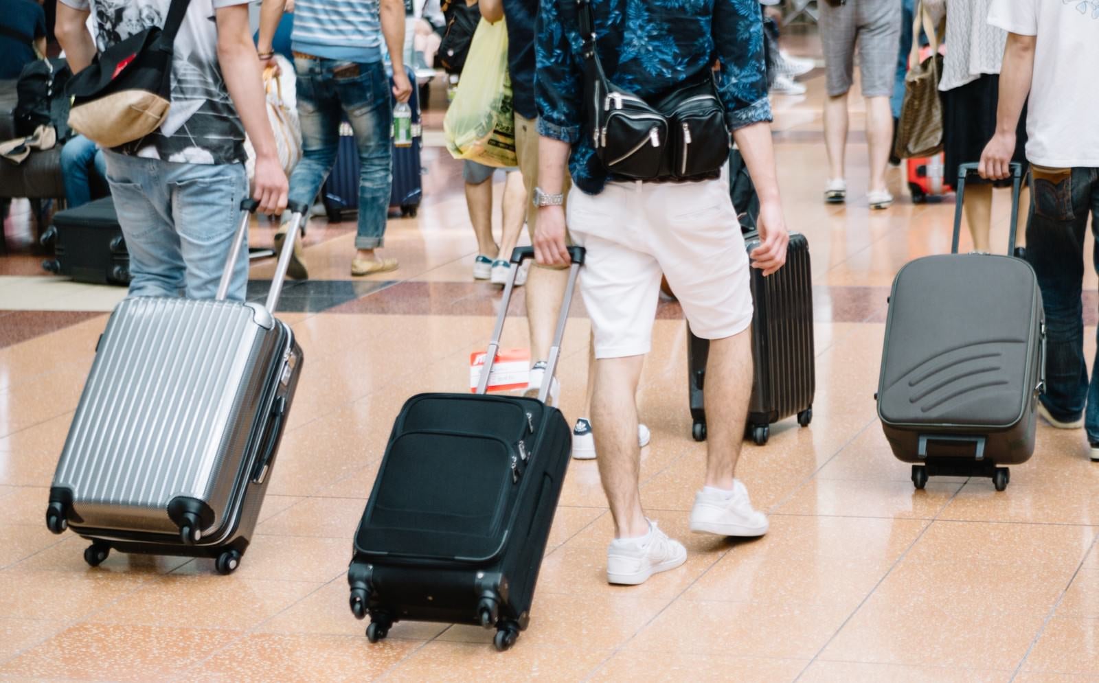 「空港でキャリーバッグを持った観光客」の写真