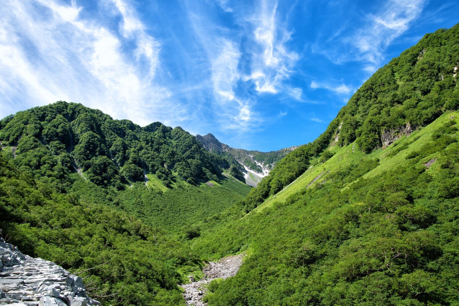 「新緑溢れる山間からかすかに見える涸沢カール」の写真