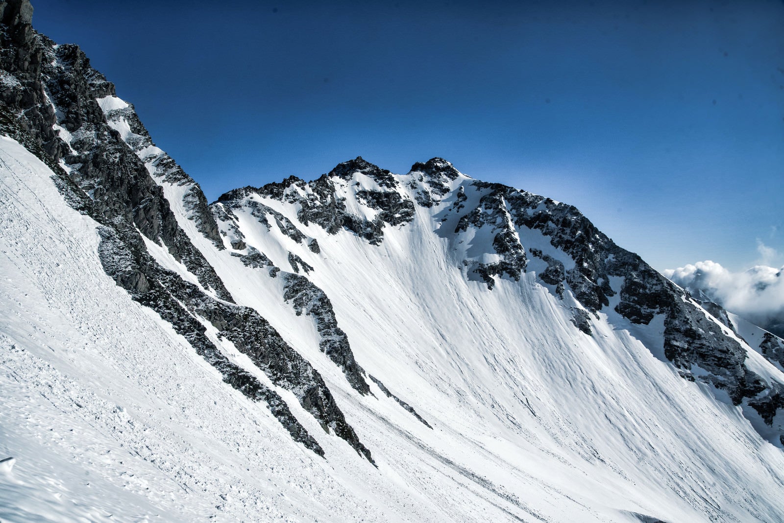 「残雪期の北穂高岳と雪の転がる跡」の写真