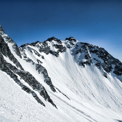 残雪期の北穂高岳と雪の転がる跡の写真