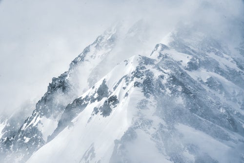 吹雪く視界不良の雪山の写真