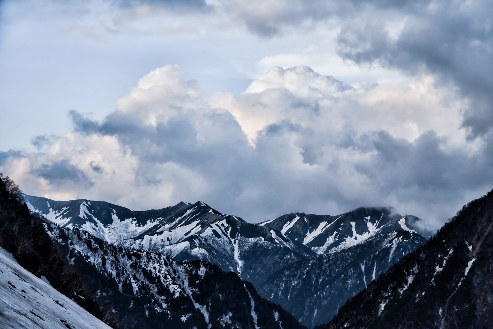 「残雪の雪山にかかる雲」の写真