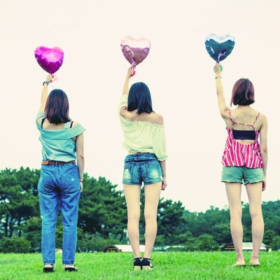ハートの風船を持った女子三人組の後ろ姿の写真