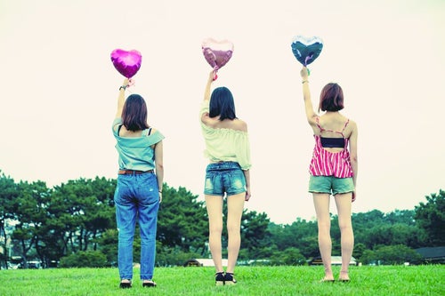 ハートの風船を持った女子三人組の後ろ姿の写真