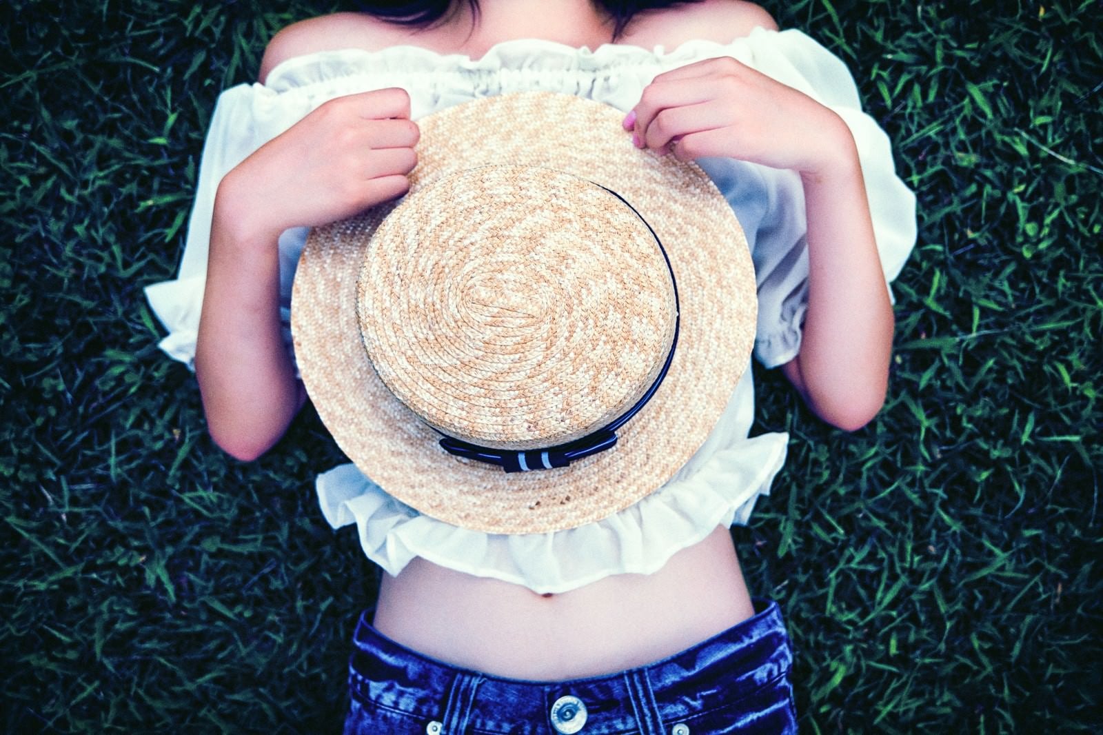 「麦わら帽子を持って横になる女性」の写真