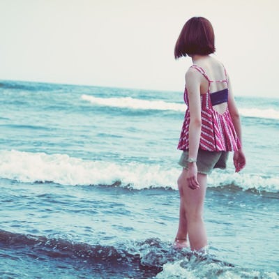 海の波と浅瀬を歩く若い女性の写真