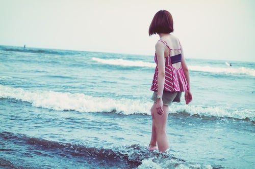 海の波と浅瀬を歩く若い女性の写真
