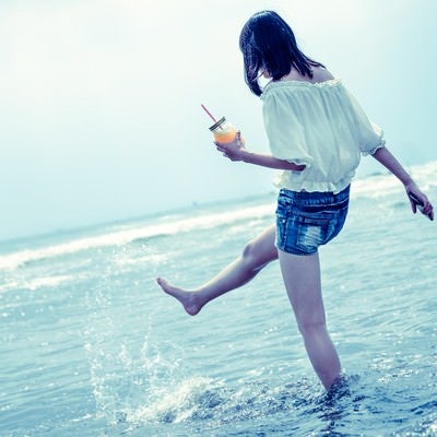 海面を蹴り上げる女性の写真