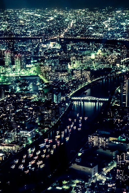 川を流れるカラフルな屋形船と都会の夜景の写真