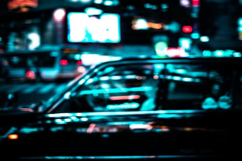 ネオンを反射するタクシーの写真
