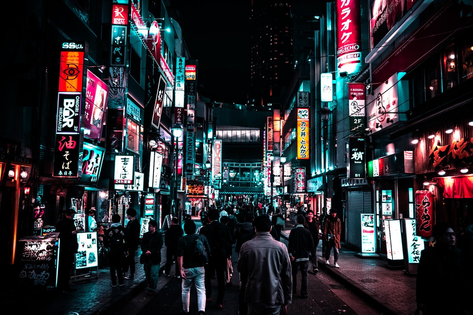 「路地裏のネオン街を渋谷駅方向に歩く人の群れ」の写真