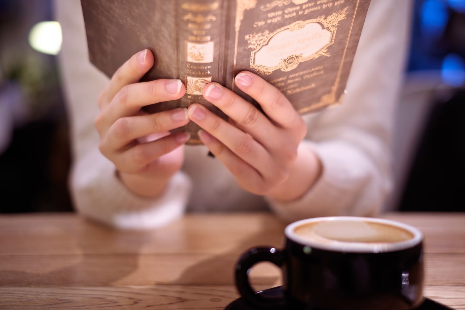 「カフェで洋書を読む女性の手元」の写真