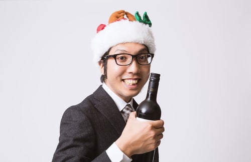サンタ帽を被ってワインボトルを握るサラリーマンの写真