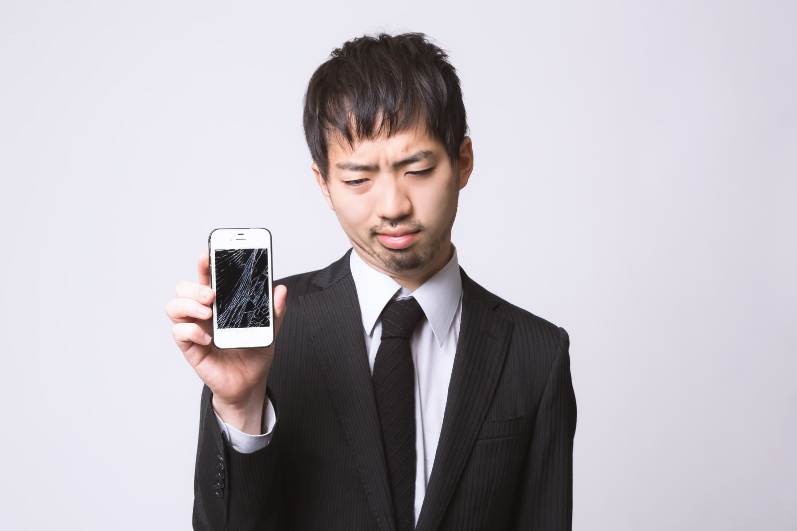 「スマートフォンを落としてガックリしている男性」の写真