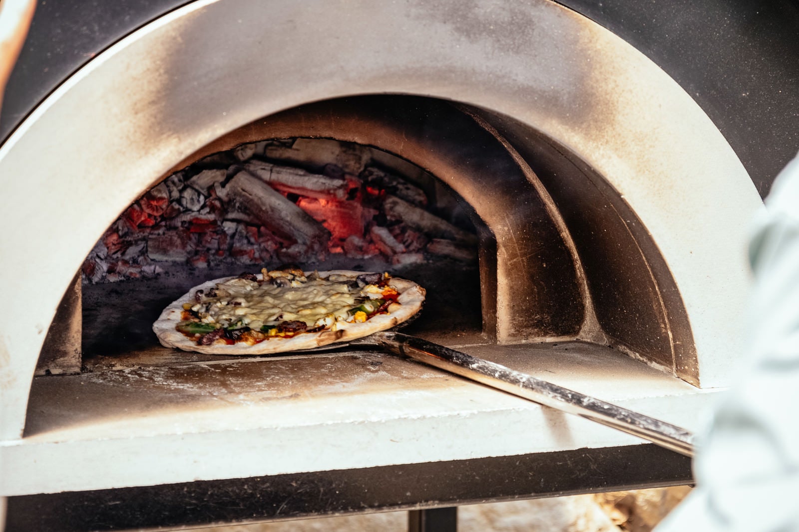 「釜から取り出されるピザ」の写真