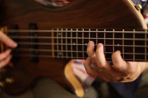 5弦ベースを使うベーシストの左手の写真