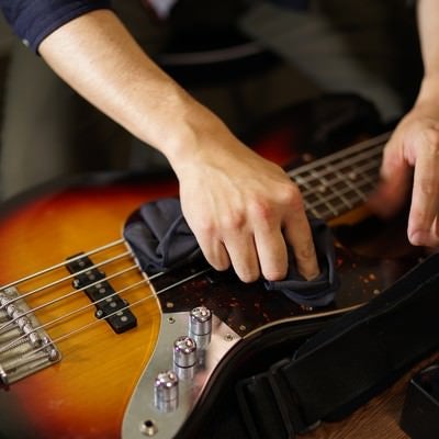 エレキベースの弦を拭く男性ミュージシャンの写真