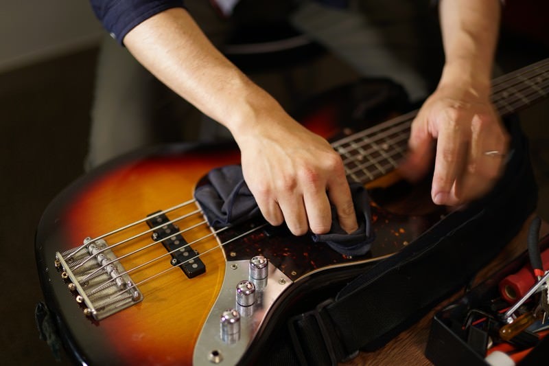 Male Musician Wiping Electric Bass Strings