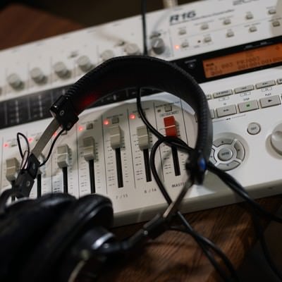 プロ仕様のマルチトラックレコーダーとモニターヘッドフォンでの音楽制作風景の写真