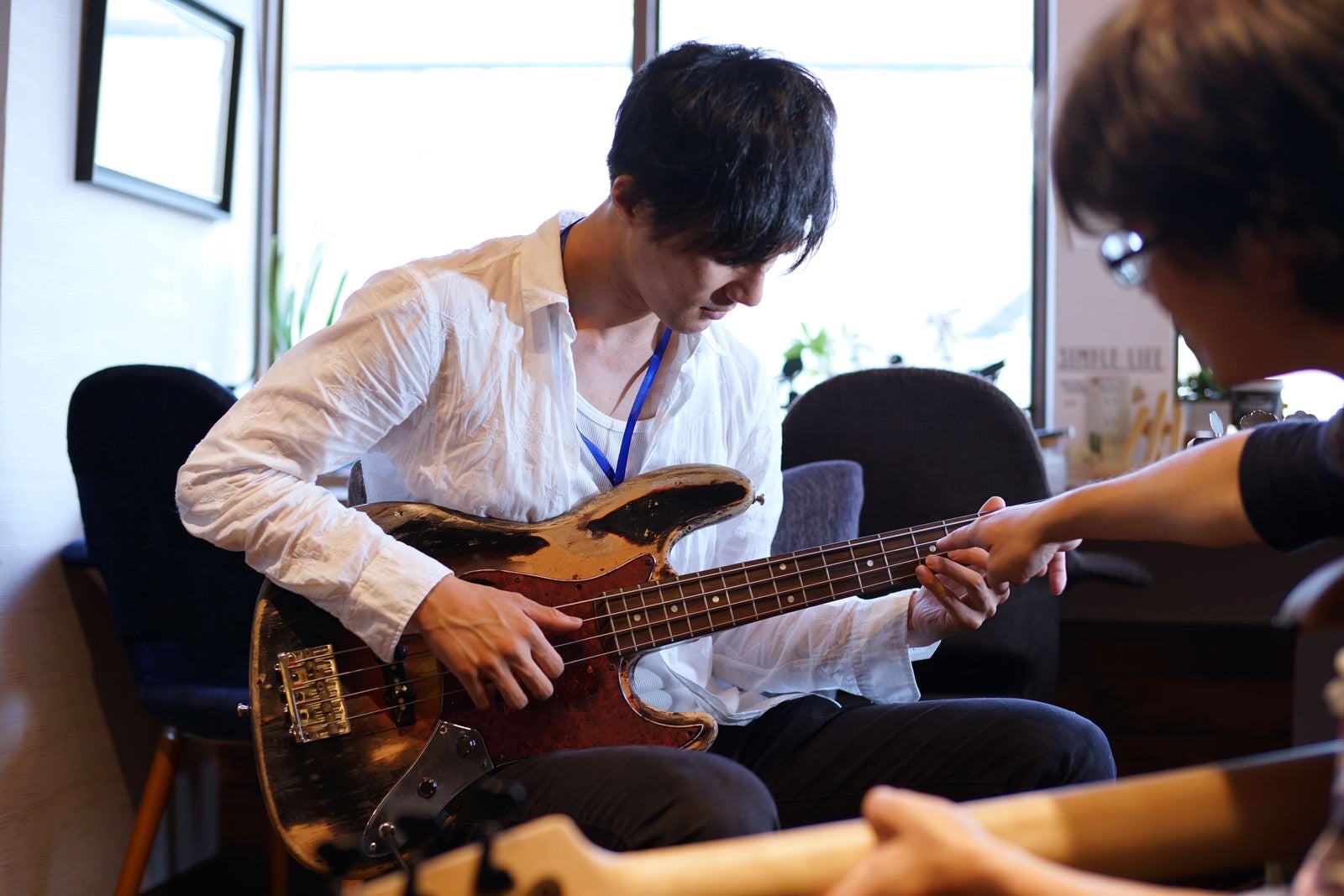 「ベースの弦のおさえかたをレクチャーするベースレッスン」の写真［モデル：村田裕章］