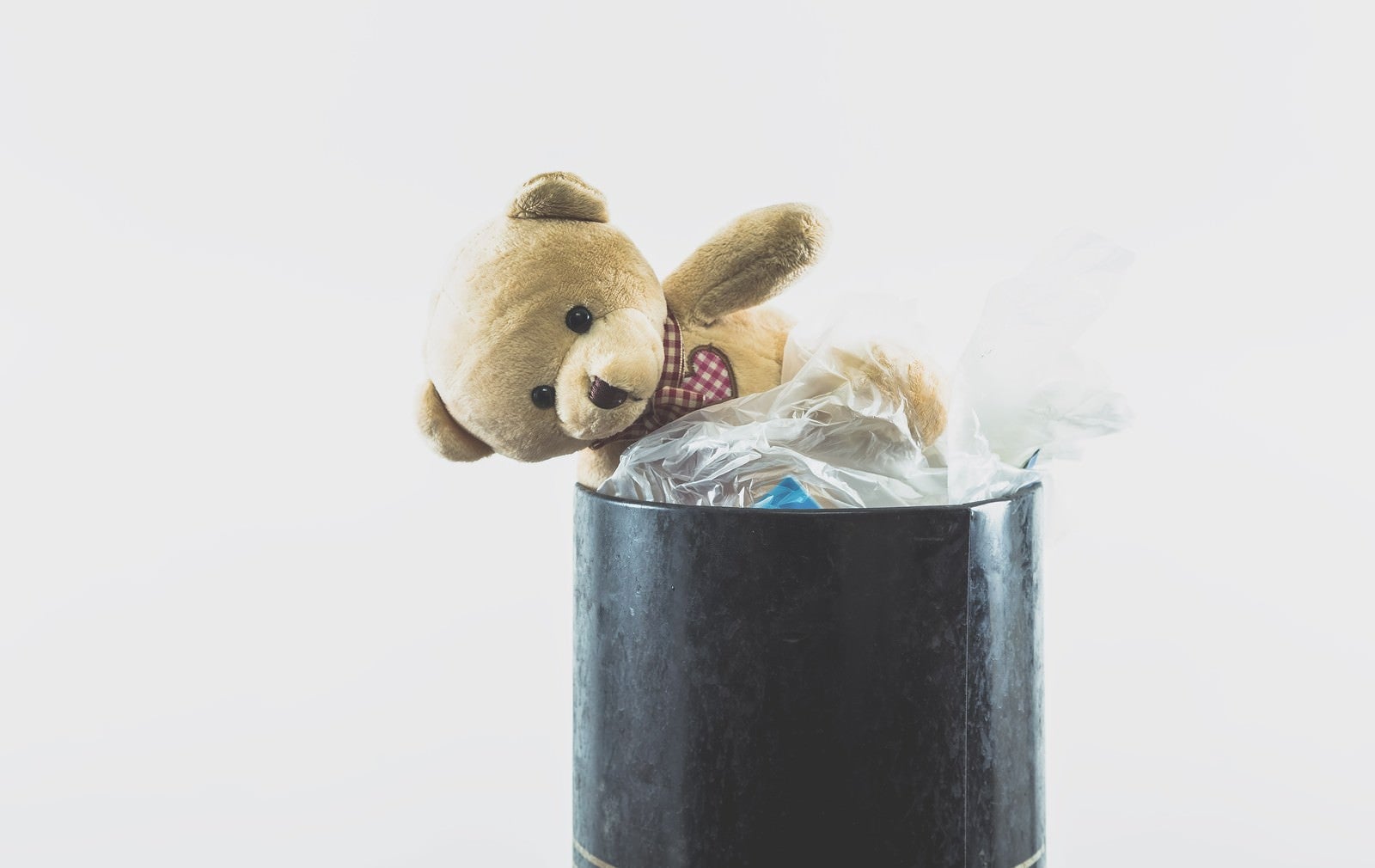 「ゴミ箱に捨てられたクマのぬいぐるみ」の写真