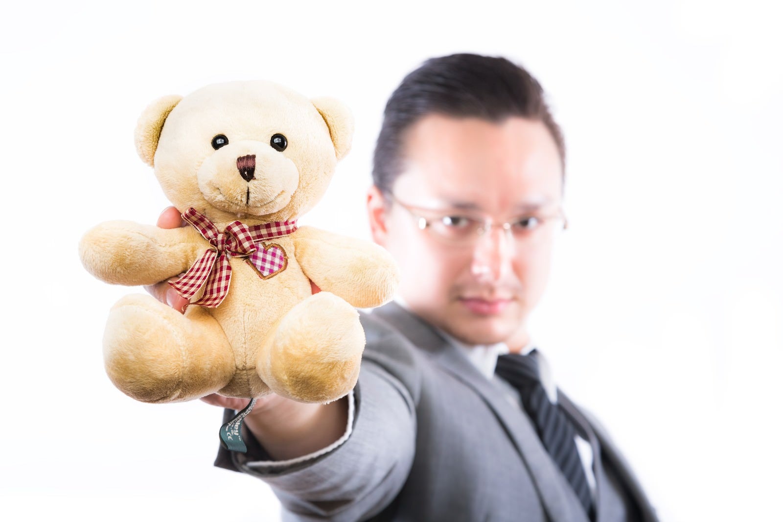 「熊のぬいぐるみを差し出す外資系ビジネスマン」の写真［モデル：Max_Ezaki］
