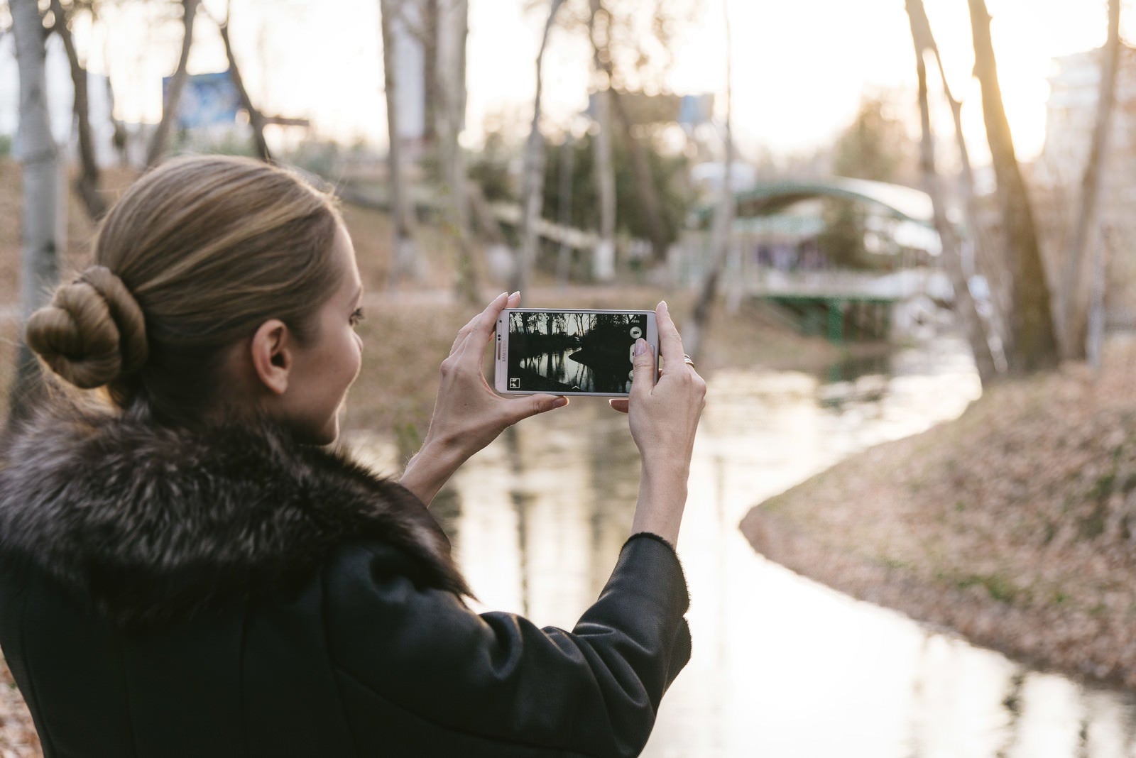 「スマートフォンで景色を撮影するブロンド美女」の写真［モデル：モデルファクトリー］