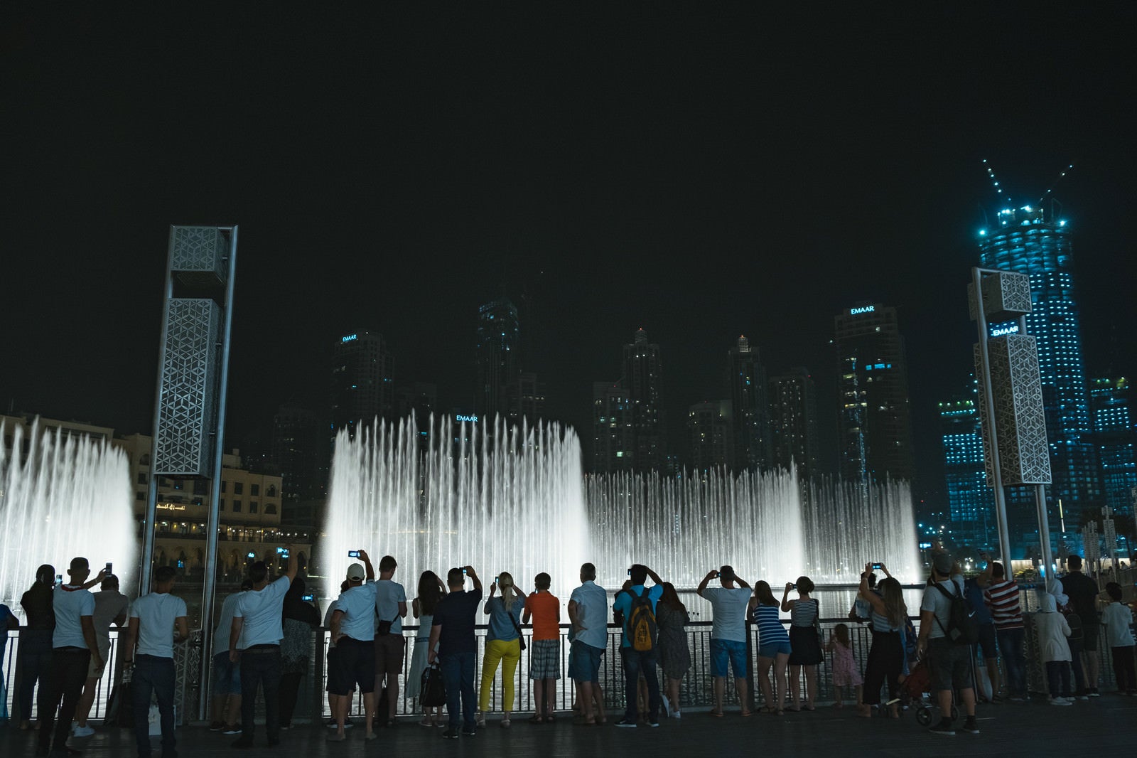「高層ビルとライトアップされた噴水に群がる観光客」の写真