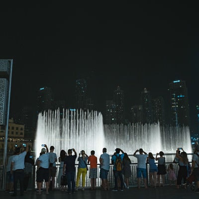 高層ビルとライトアップされた噴水に群がる観光客の写真