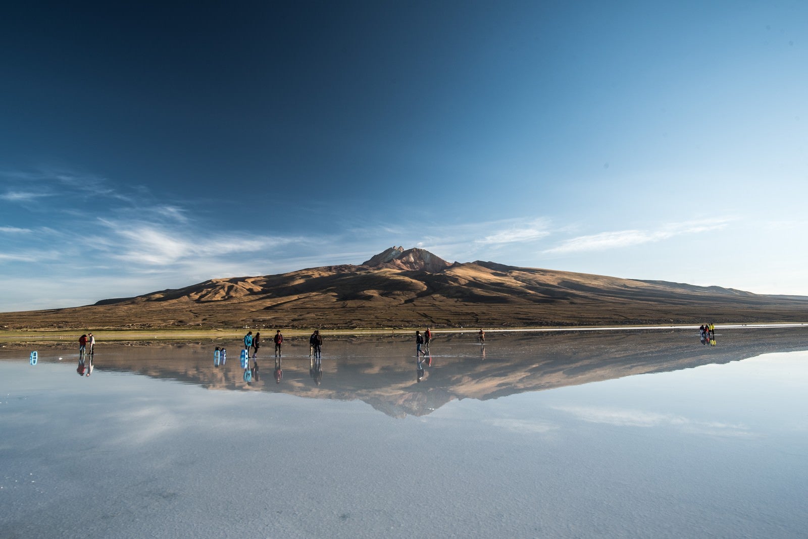 「ウユニ塩湖に訪れた観光客と鏡のように映り込む山」の写真