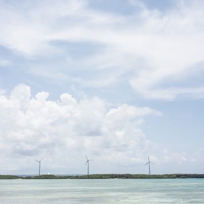 透き通る海と風力発電の写真