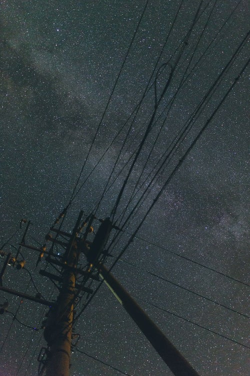 電柱のシルエットと輝く星空の写真