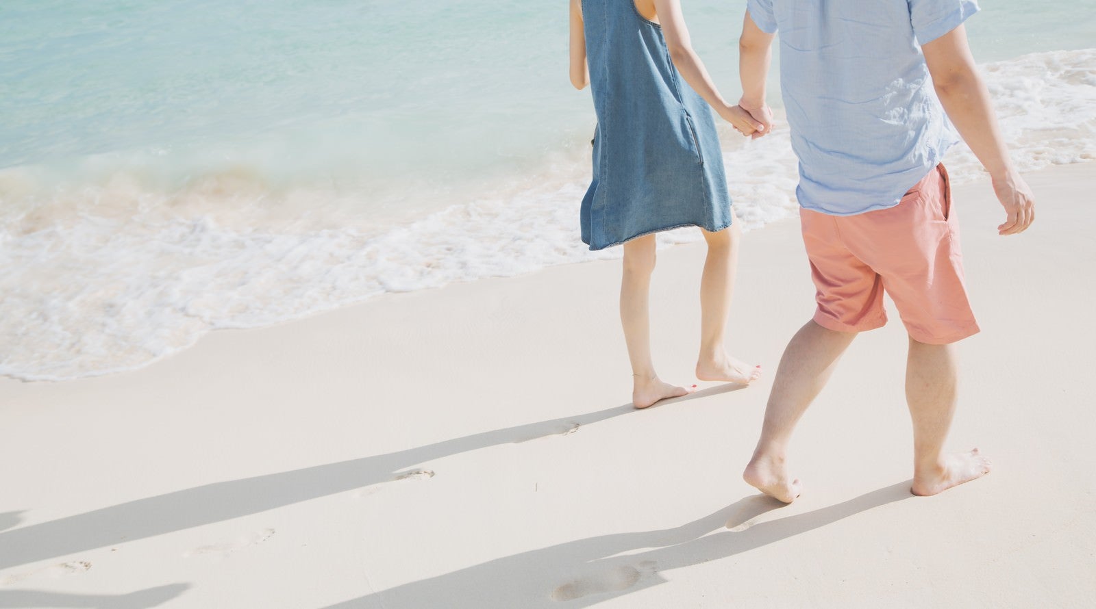 「波打ち際を歩く恋人と足あと」の写真