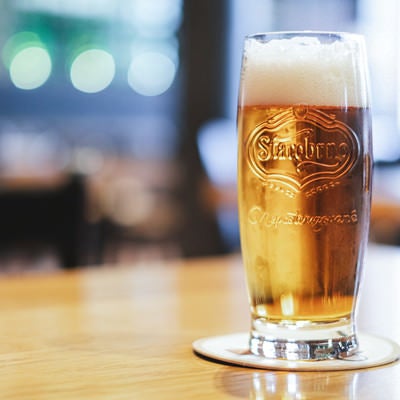テーブルの上に置かれたグラスビール（チェコ共和国・ブルノ）の写真