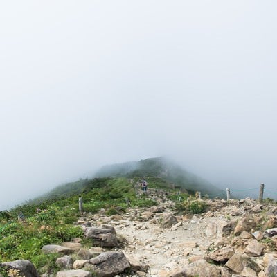 視界不良の雲の中へと進む登山者の写真