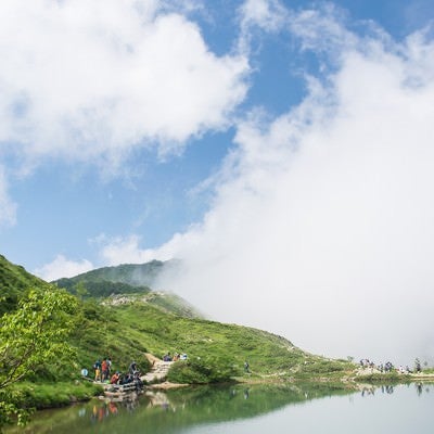 湖面に映る雲と登山者の写真