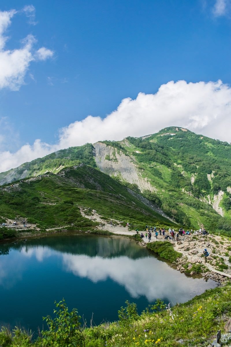 「湖畔に映る景色と登山者」の写真