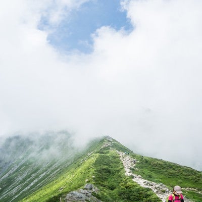 雲の中の尾根を進む登山者の写真