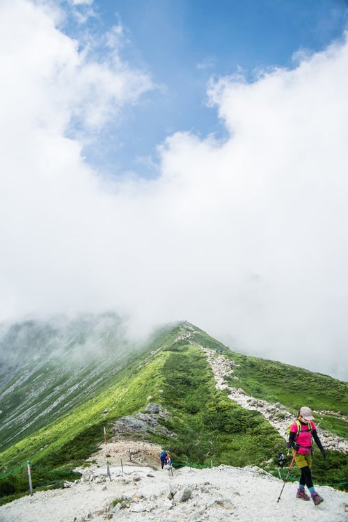 雲の中の尾根を進む登山者の写真