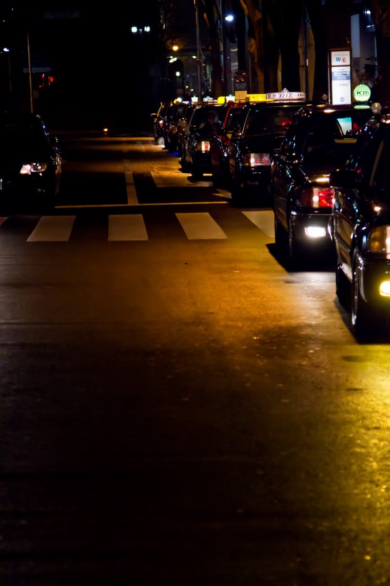 「客待ちで縦列する夜のタクシー」の写真