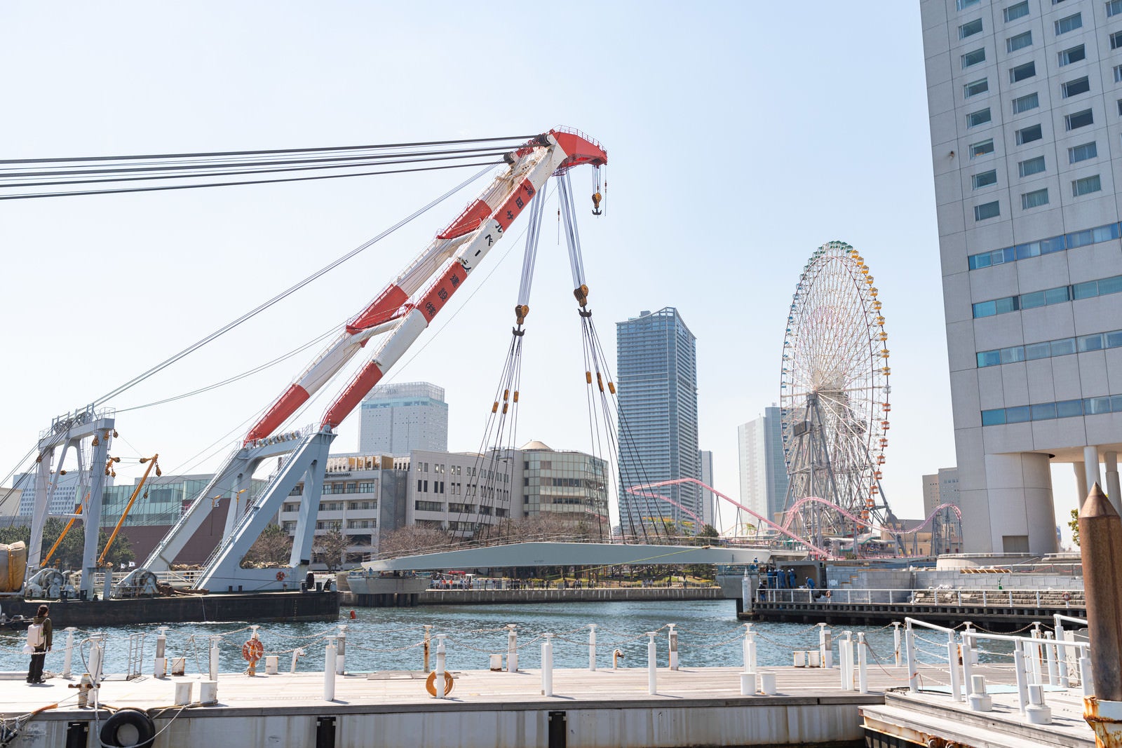 「MM21地区の新設デッキ「女神橋」をクレーンで吊るす様子」の写真