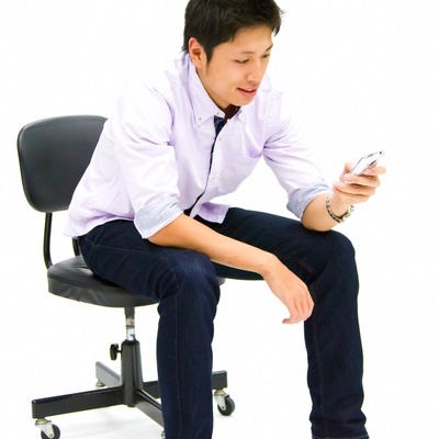 携帯を操作する青年の写真