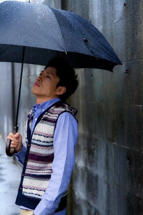 雨の日に傘を差す青年の写真