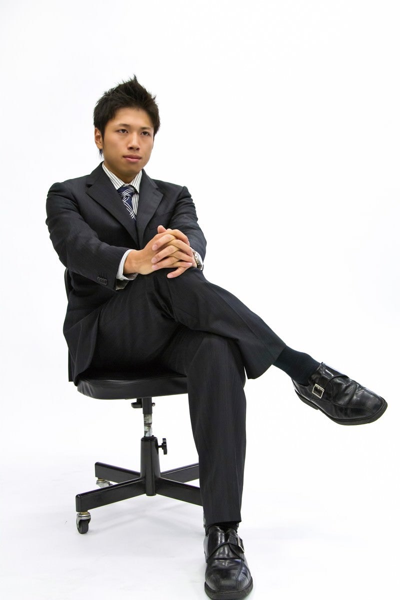 「椅子に座って足を組むサラリーマン」の写真［モデル：恭平］