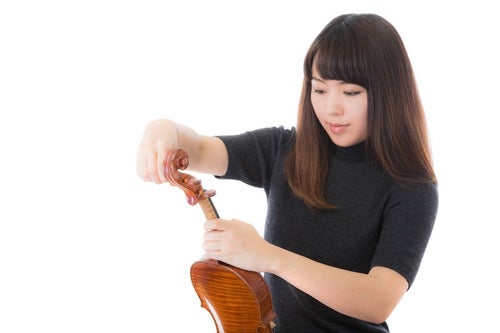 ヴァイオリンの弦を張り替える女性の写真