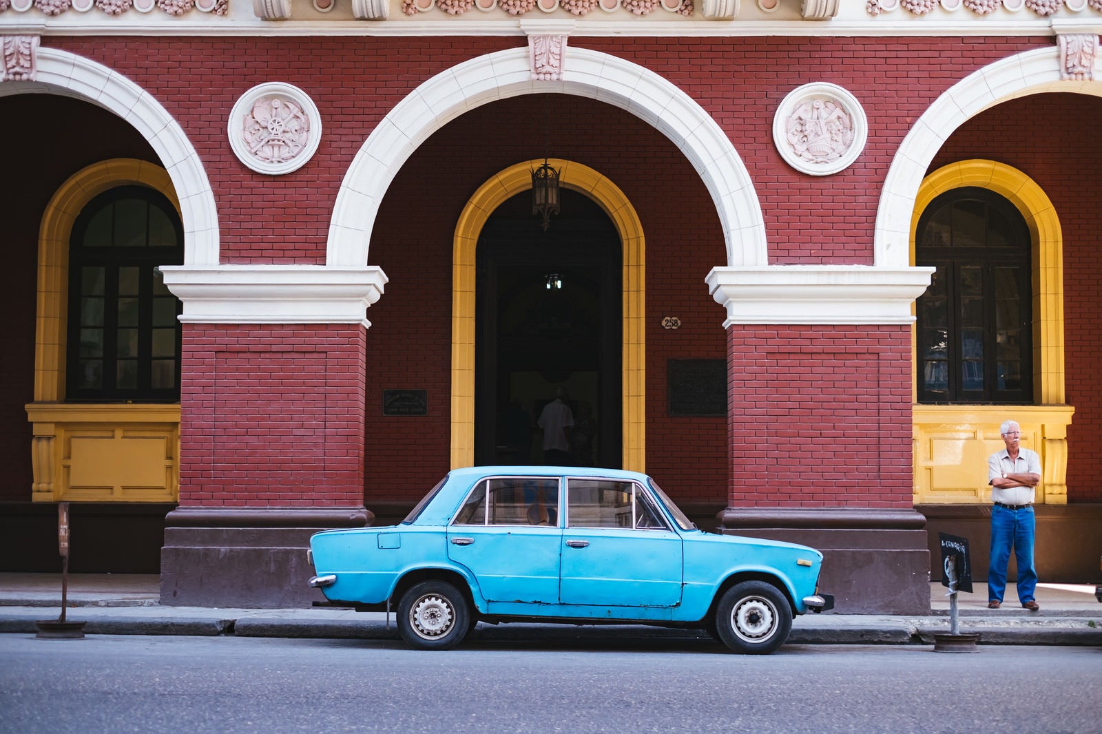 「建物の前に駐車中の青い車（キューバ）」の写真